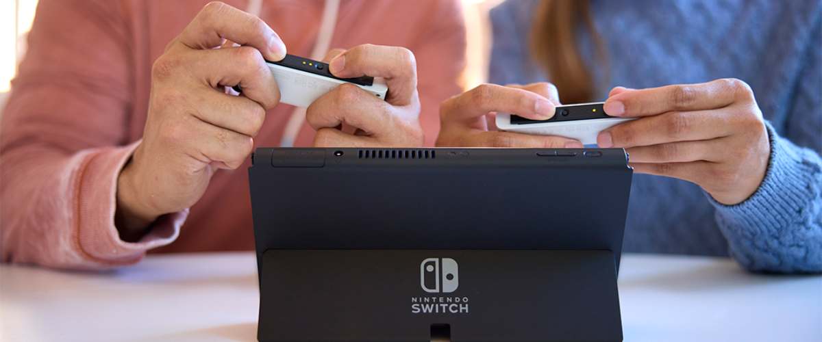 Mehe ja naise käed hoidmas Nintendo Switch Lite pulte
